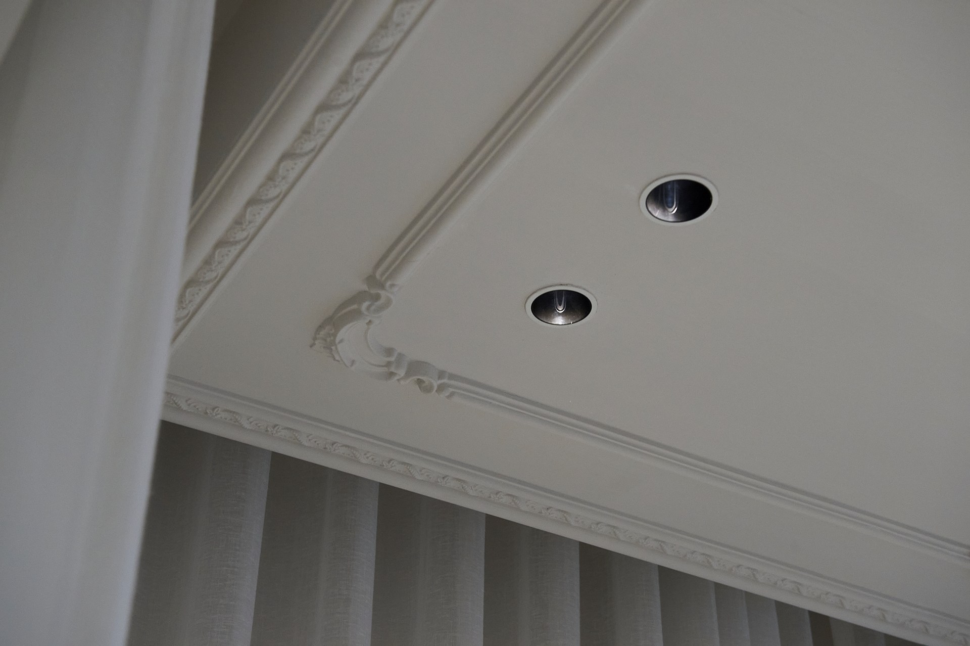 Decorative chair rails applied to the ceiling, accentuating recessed spotlights and ceiling proportions.