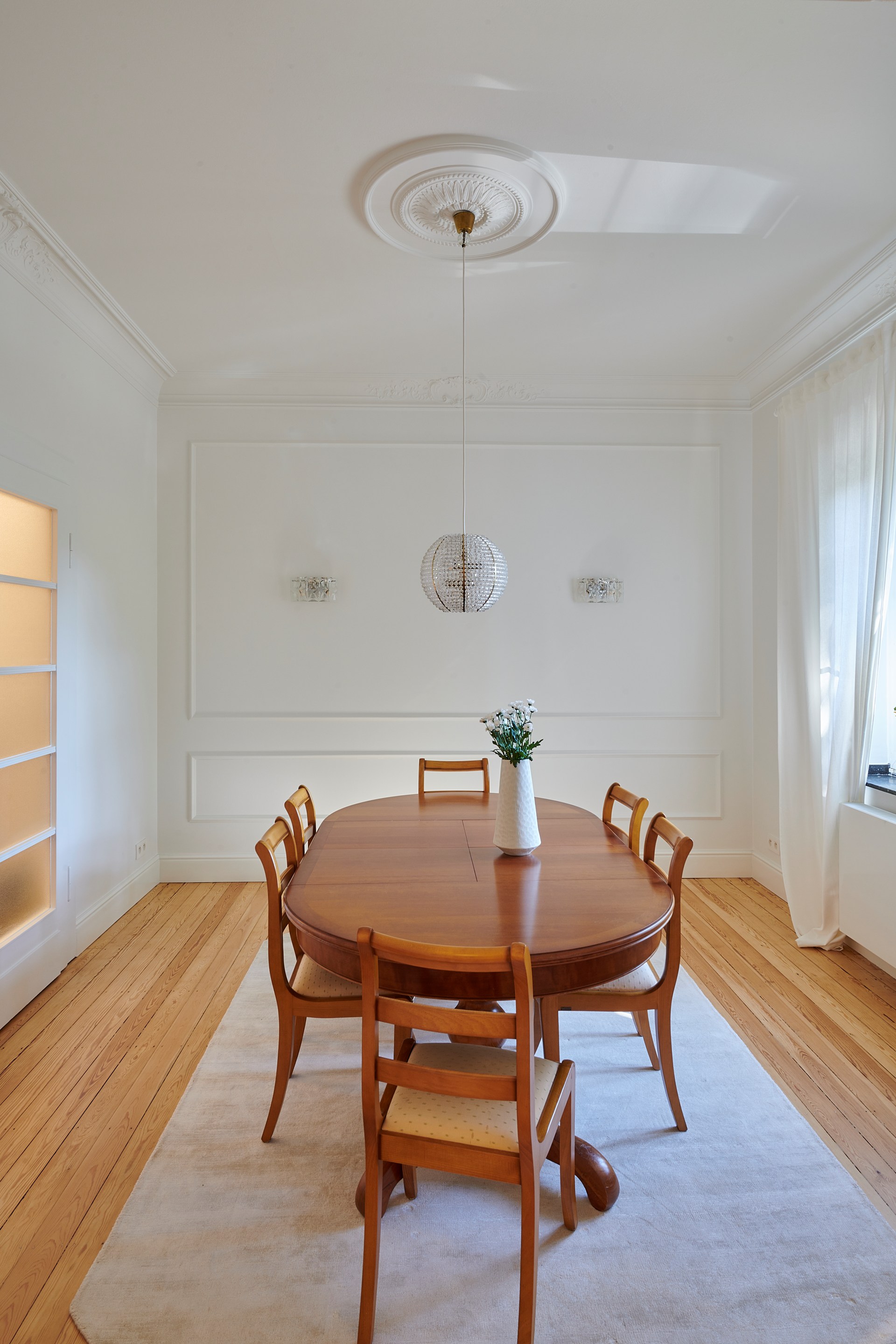 Decorative ceiling rose and mouldings enhancing a refined dining room with pendant lighting.