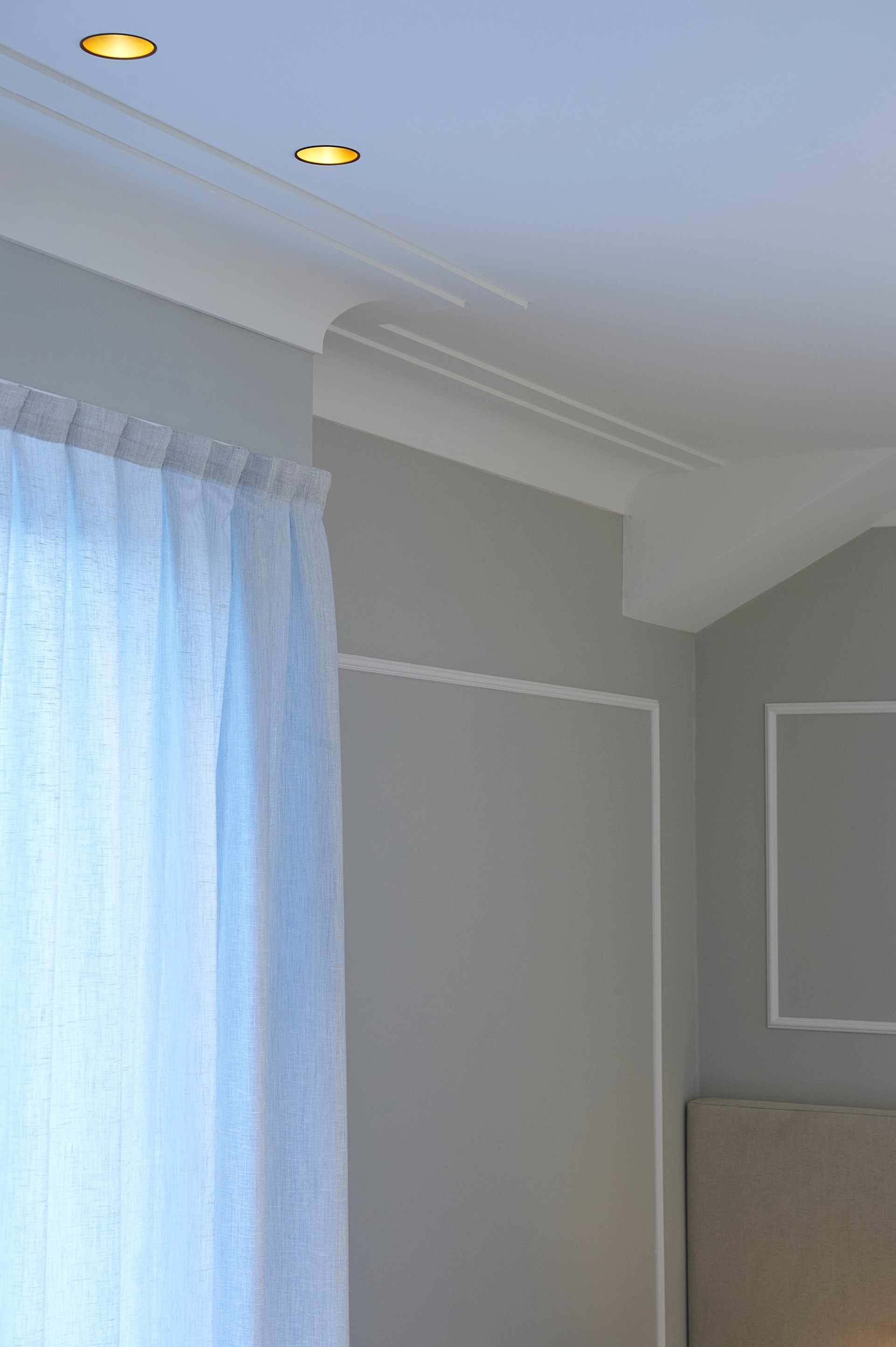 Minimalist cornices defining the transition between wall and ceiling in a modern interior.